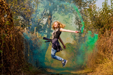 Happy girl laughing and running with green color smoke bomb in forest.