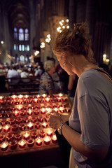 Obraz na płótnie Canvas Woman lighting candles in Notre Dame, Paris