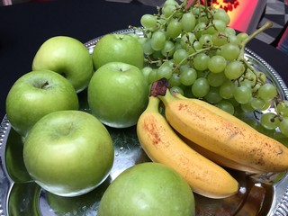 Silver tray full of fresh fruits: green apples, grapes and bananas