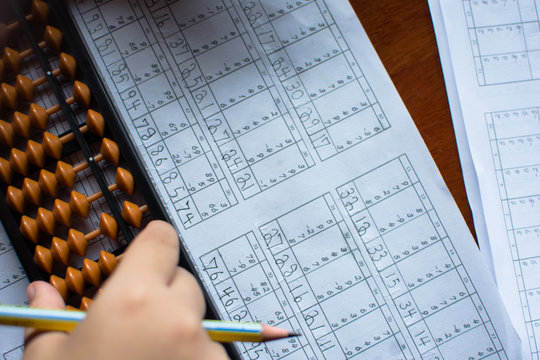 Cute little girl playing with abacus at home. Smart child learning to count.