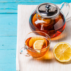 Glass cup of tea with lemon and glass teapot.