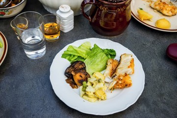 Fried fish,vegetable,lettuce and potoato salad on table with drink and food.