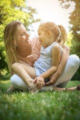 Fototapeta premium Mother and daughter outdoors in a meadow. Mother and daughter having funny conversation.