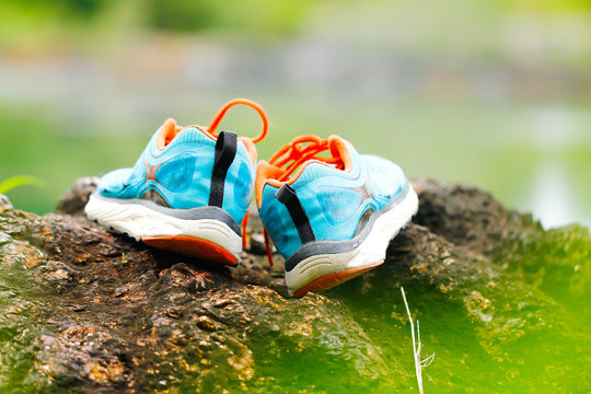 Stock Photo - Shoes on the rocks next to a mountain lake