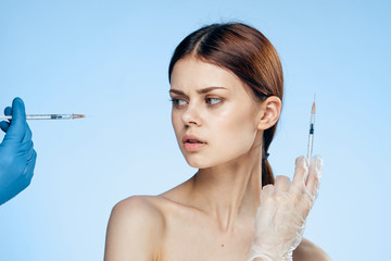 Beautiful young woman on a blue background holds a syringe, medicine, plastic