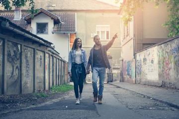 Couple holding hands outdoors. Boyfriend showing something to his girlfriend.