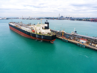 container ship in import export and business logistic.By crane , Trade Port , Shipping.Tugboat assisting cargo to harbor.Aerial view.