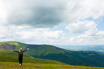 Young woman standing on cliff's edge and looking into a wide valley