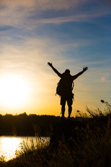 Young tourist with hands in the air, standing on a rock. A beautiful mountain landscape.