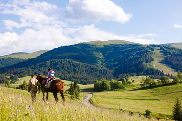 Obraz premium Lovely equestrian - little girl is riding a horse, mountain in the background