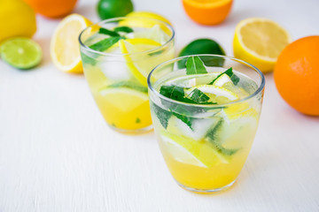Fresh citrus lemonade with limes, mint and lemons in glasses on white table