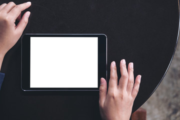 Mockup image of a woman using black tablet pc with blank white screen on a black table background