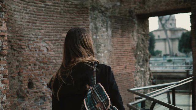 Young woman going through Roman Forum in Rome, Italy. Girl is capturing the beauty of old walls and enjoying the view.