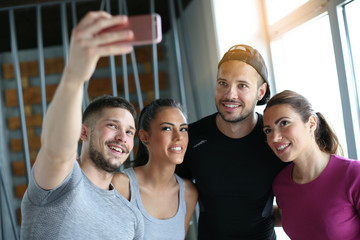 Group of smiling people making self-picture in gym. People workout in gym.