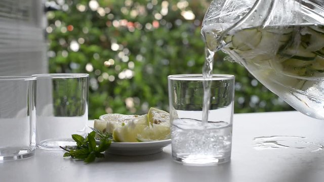 pouring of water with mix of herbs and vegetables in the glass