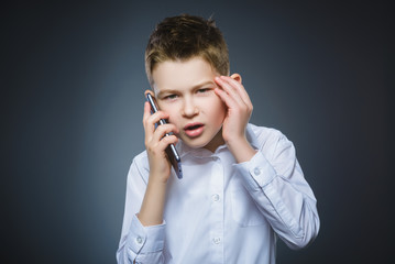 Portrait of offense boy with mobile or cell phone. Negative human emotion