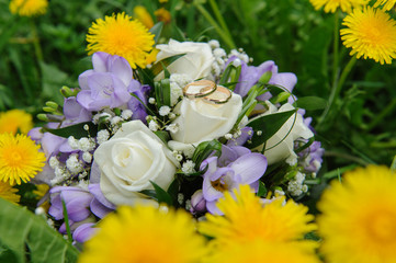 Wedding bouquet and wedding rings in dandelions