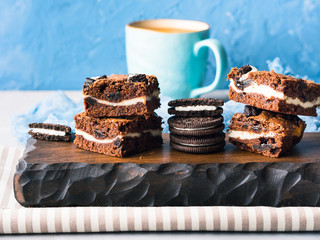 Cream cheese chocolate layer brownies with cookies on wooden serving board