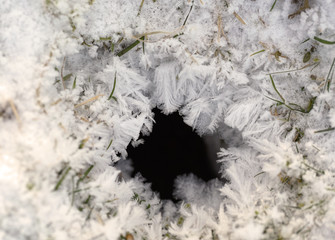 Schneekristalle, Eiskristalle in winterlicher Landschaft um ein Erdloch