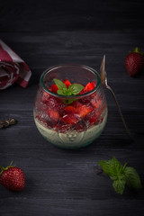 Homemade Italian dessert panna cotta with fresh strawberries and mint on a dark wooden background