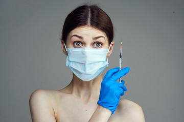 Beautiful young woman on a gray background holds a syringe, medicine, plastic