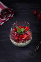 Homemade Italian dessert panna cotta with fresh strawberries and mint on a dark wooden background