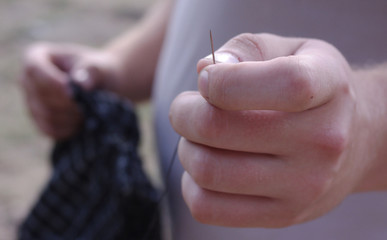 Obraz premium Needle with thread in the man's hand