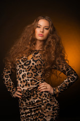 Girl in leopard dress and black shoes on brown background