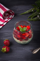 Homemade Italian dessert panna cotta with fresh strawberries and mint on a dark wooden background
