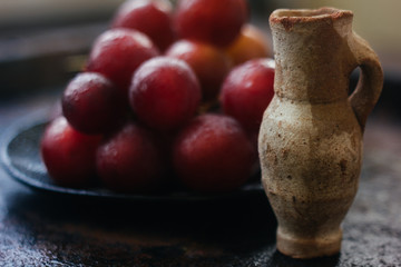 Small clay jug behind the grapes