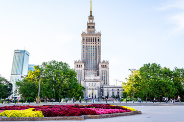 Fototapeta premium Pałac kultury i nauki w Warszawie w słoneczny dzień z błękitne niebo i zielone drzewa.