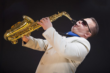 Fototapeta na wymiar Saxophonist playing saxophone. The soloist, saxophonist plays the saxophone. Dressed in a suit. Man.