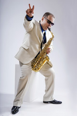 Fototapeta premium Saxophone only. Saxophonist. Caucasian man with a saxophone. Dressed in a white suit. The studio silhouette on a white background.