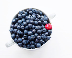 Fresh  blueberries in a cup on a white surface. Closeup, top view.