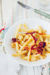 Poutine fries with tomato sauce and cheese on white table.