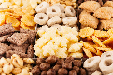 Corn flakes various shape and flavor - rings, stars, balls, pads, chocolate top view, decorative pattern background.