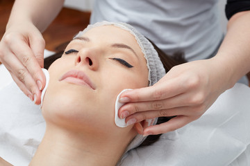 Fototapeta na wymiar Relaxing beautiful woman having a massage for her skin on a face in beauty salon