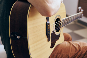 Fototapeta premium Young guy with a beard on a light background playing the guitar
