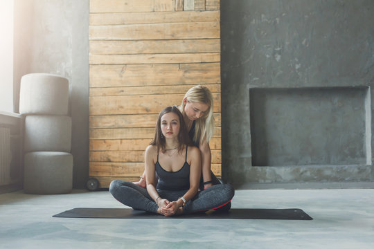 Young woman with yoga instructor in fitness club, lotus pose