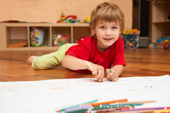 Cute little boy child kid drawing lying on floor  at home

