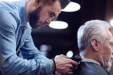 Nice male hairdresser being focused on his job