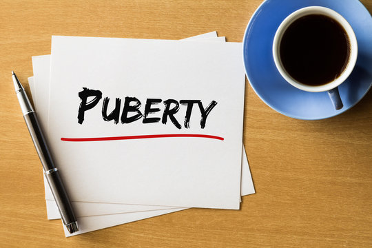 Puberty - handwriting on papers with cup of coffee and pen, concept