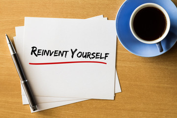 Reinvest yourself - handwriting on papers with cup of coffee and pen, Business concept