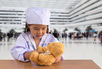 Asian girl playing as a doctor care bear doll