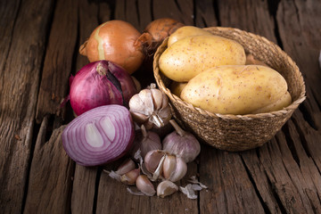Ripe onion, Potato and garlic on wooden background.