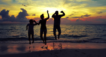 Glückliche Familie springt am Meer beim Sonnenuntergang 

