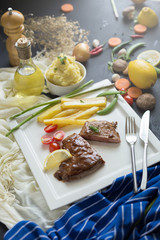 Fresh grilled meat. Grilled beef steak on white plate French fries and Mashed potato with spoon, in serving bowl