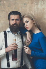 Woman and man posing with bottle and glass of liqueur