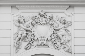 angel statues holding emblem - sculptures on house facade