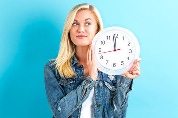 Young woman holding a clock showing nearly 12 